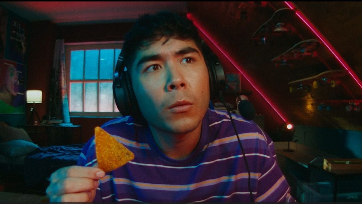 A gamer holds up a Doritos chip in an ad promoting the brand's crunch-cancellation software